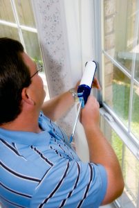 Man Performing Home Air Quality Energy Audit - Caulking Windows